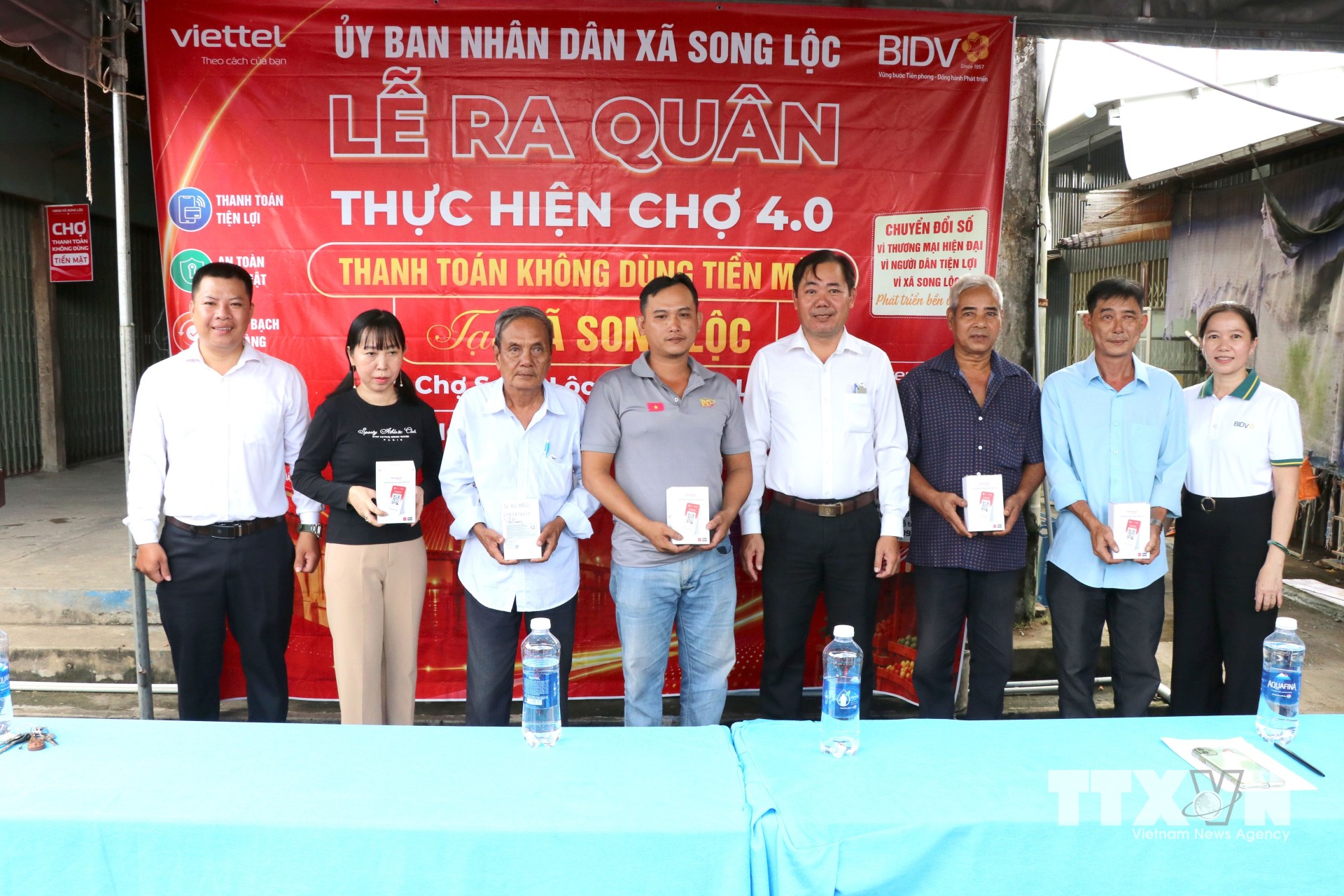 Lãnh đạo xã Song Lộc, tỉnh Vĩnh Long, và các đơn vị đồng hành trao bảng mã QR và loa thông báo cho các tiểu thương tại lễ ra quân. (Ảnh: Thanh Hòa/TTXVN)